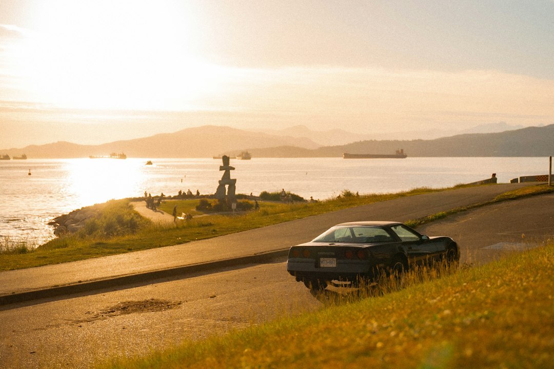 Luxury sedan driving along a coastal road at sunset