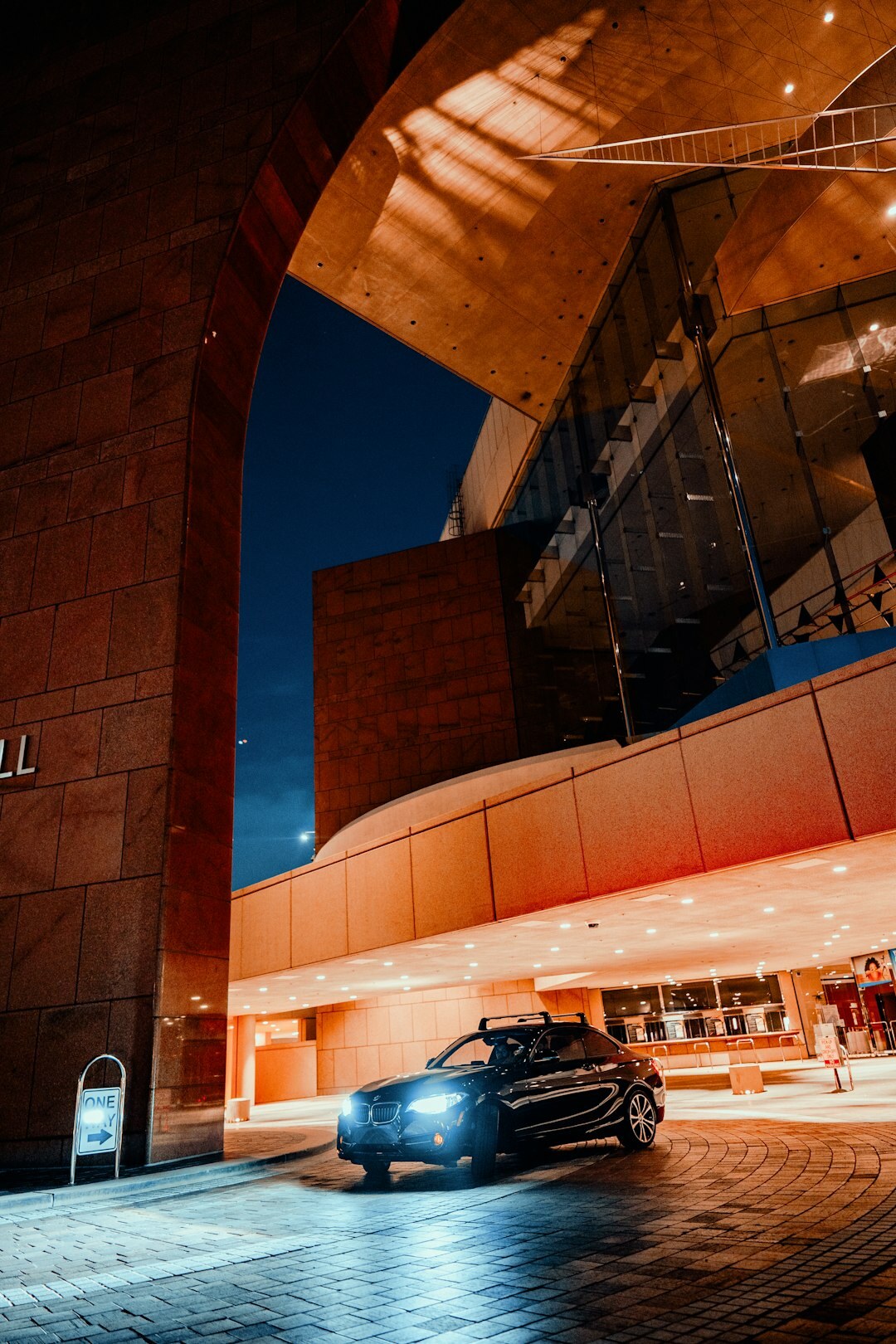 Luxury car parked in front of a modern building at night